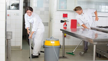 Personnel de cuisine nettoyant un sol de cuisine professionnelle