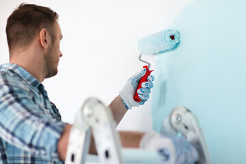 Peintre peignant un mur de couleur bleu ciel