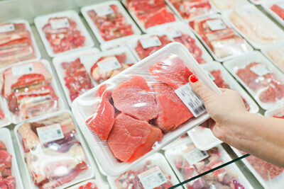 Personne montrant de la viande emballée dans un supermarché