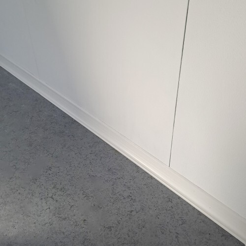 Pose de plinthes blanches sur un mur régulier