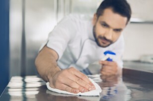 Vue d'une personne nettoyant un plan de travail en inox alimentaire avec un chiffon doux