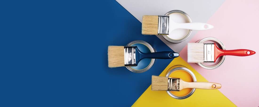 Différent pots de peinture de couleurs bleu, jaune, rose et blanche avec pinceau dessus pour peinture alimentaire