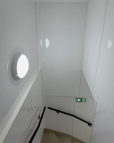 Escaliers et espace de circulation d'un restaurant avec murs habillés de plaques PVC blanches