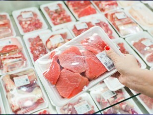 Personne montrant de la viande emballée dans un supermarché