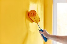 Passage d'une peinture d'ambiance alimentaire de couleur jaune au rouleau sur un mur