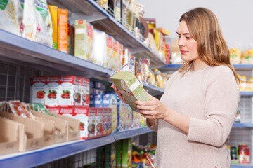 Femme lisant l'étiquette d'un produit dans  un supermarché